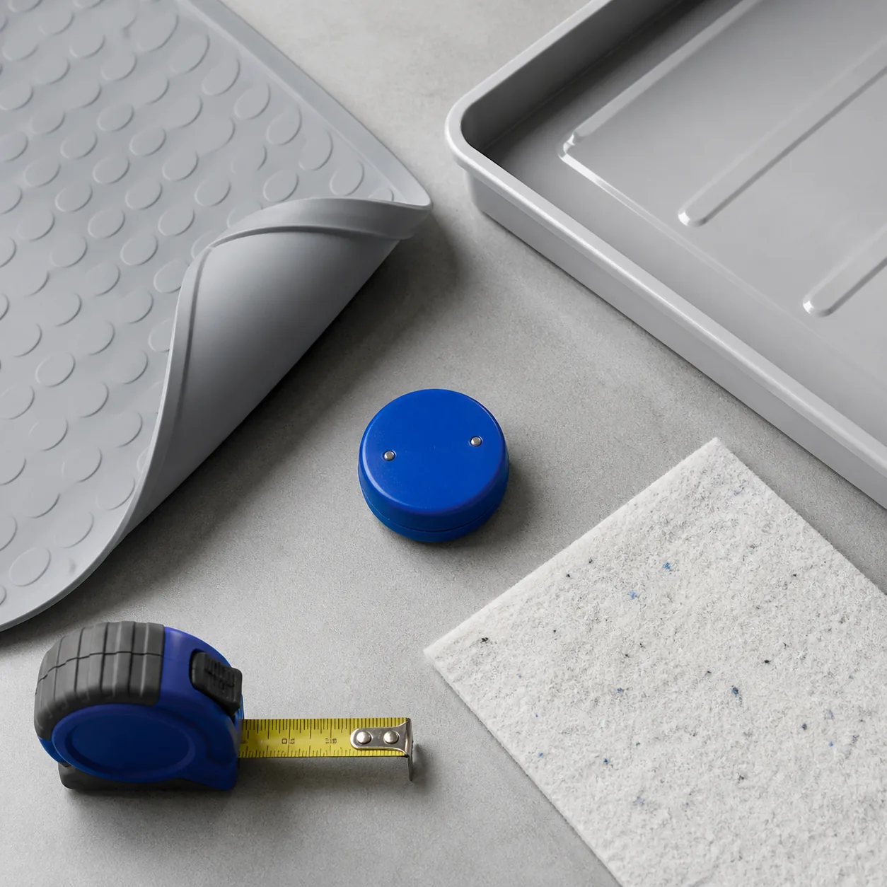 Waterproof mat, rigid tray, liner, sensor, and measuring tape arranged for comparison